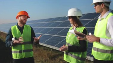 Mühendisler projeyi tartışıyorlar. Verileri yazıyorlar. Arka planda güneş panelleri var. 4K