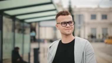 Tren istasyonunda bir adam toplu taşıma durağında yürüyor. Gözlük takıyor. O, kameraya bakıyor. 4K