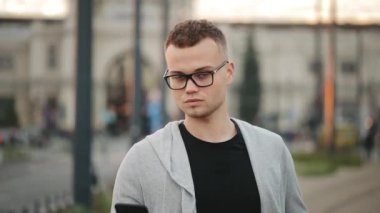 Tren istasyonunda bir adam duruyor ve mesaj atıyor. Başını kaldırıyor ve kameraya bakıyor. 4K