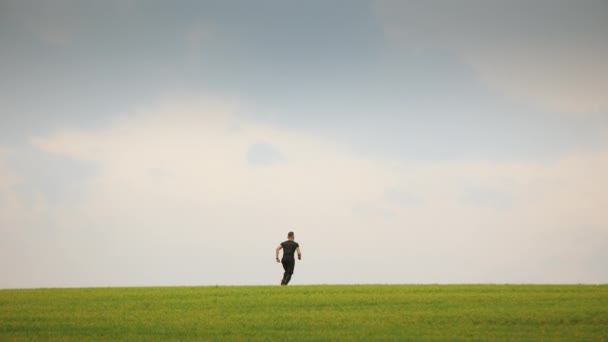 De sporter springt en verheugt zich. Hij staat op het groene gras. Lopende training. 4K — Stockvideo