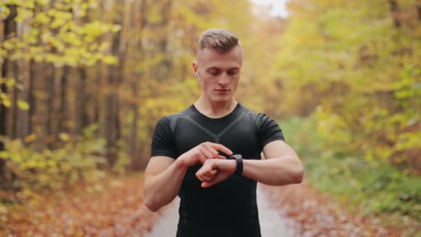 Sportovec začíná trénovat na hodinkách a zapíná hudbu ve sluchátkách. Běžící trénink. 4K — Stock video