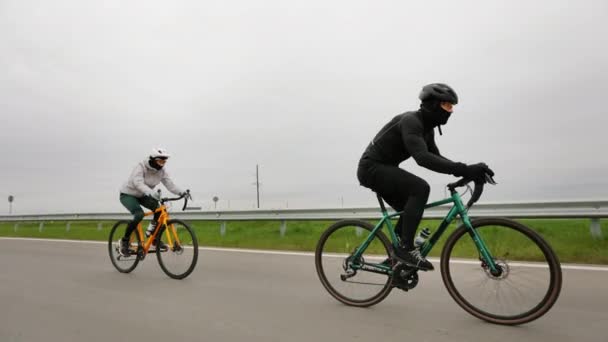 Два спортсмени тренуються на велосипеді. Вони їздять по шосе і прискорюються. Тренування в холодну пору року. 4-кілометровий — стокове відео