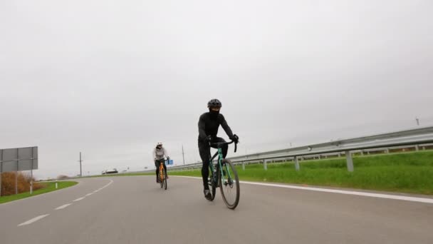Po trati jezdí sportovci na kolech. Zrychlují a otáčejí se. Trénink v chladné sezóně. 4K — Stock video
