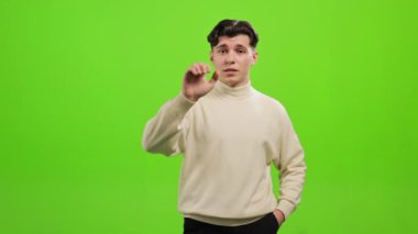 Adam ayakta duruyor ve kameraya bakıyor. Elini kaldırıyor ve 