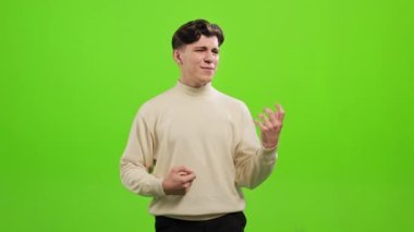 Adam ayakta duruyor ve kameraya bakıyor. O gitar çaldığını ve şarkı söylediğini hayal ediyor. O, yeşil bir arka planın üzerinde duruyor. Yeşil ekran. 4K