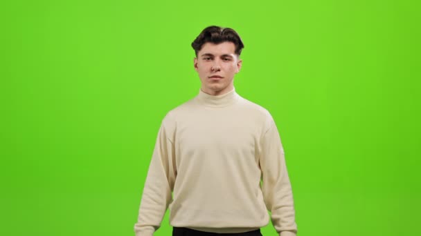 The man is standing and looking at the camera. He is raising his hand and holding the light bulb. He is standing on a green background. Green screen. 4K — Stock Video