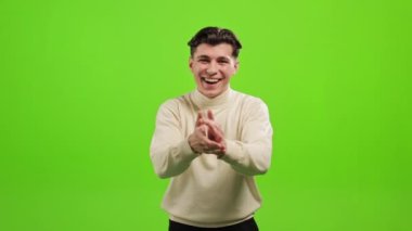Adam ayakta duruyor ve kameraya bakıyor. Çok gülümsüyor ve ellerini çırpıyor. O, yeşil bir arka planın üzerinde duruyor. Yeşil ekran. 4K