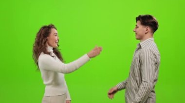 Bir erkek ve bir kadın ayakta duruyor ve birbirlerine bakıyorlar. Beş dakika veriyorlar. Yeşil bir arka planda duruyorlar. Yeşil ekran. 4K