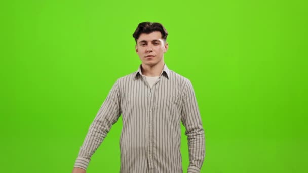 The man is standing and looking at the camera. He is picking up the bank card and holding it. He is standing on a green background. Green screen. 4K — Stock Video