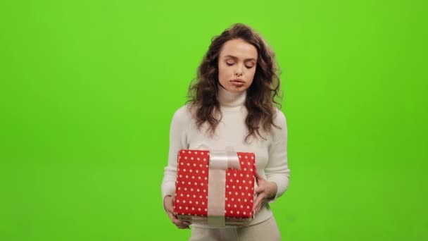女は立ってカメラを見ている。彼女は失望し贈り物を捨てる。彼女は緑の背景に立っている。緑の画面だ。4K — ストック動画