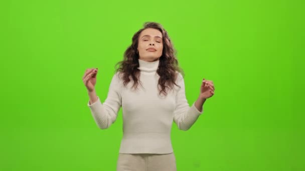 La femme est debout et regarde la caméra. Elle étend ses mains et médite. Cours de yoga. Elle est debout sur un fond vert. Écran vert. 4K — Video