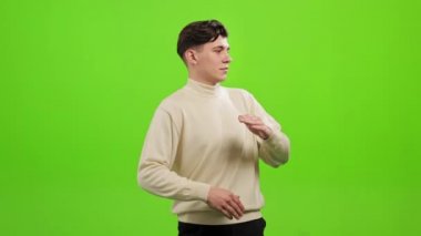Adam ayakta duruyor ve kameraya bakıyor. Parmaklarını şaklatıp dans ediyor. O, yeşil bir arka planın üzerinde duruyor. Yeşil ekran. 4K