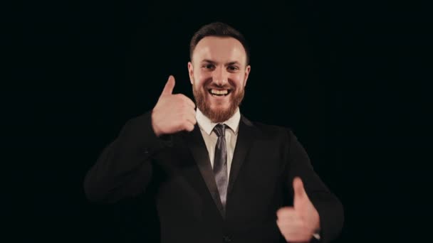 A man in a suit is standing on stage and looking at the camera. He is smiling. He is pointing his fingers up. Portrait shooting. 4K — Stock Video