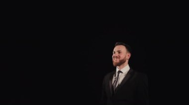 The man is lifting the goblet and rejoicing. He is standing on the stage and the spotlight is shining on him. Hes wearing a suit. 4K