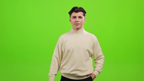 The man is standing and looking at the camera. He is picking up the light bulb and looks at it. He is smiling. He is standing on a green background. Green screen. 4K — Wideo stockowe