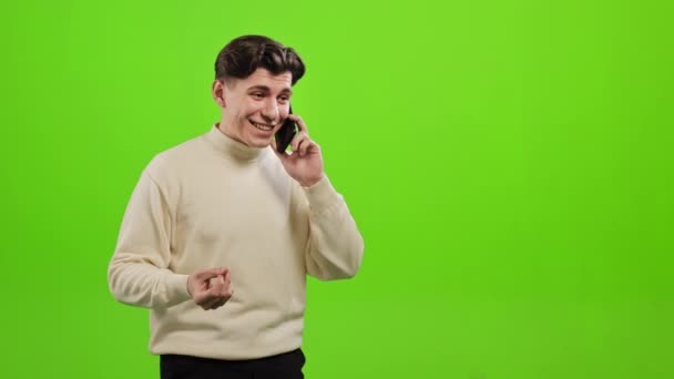 A man is standing and emotionally talking on the phone. He is standing on a green background. Green screen. 4K — Vídeo de Stock