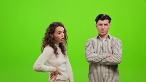 A woman is quarreling with a man. He is standing and looking at the camera. They are standing on a green background. Green screen. 4K — Αρχείο Βίντεο