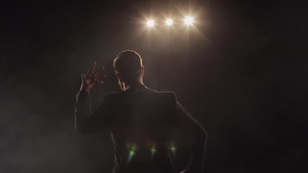 A man is performing on stage. He is waving his arms emotionally. The spotlight is shining on him. Hes wearing a suit. 4K — Stock Video