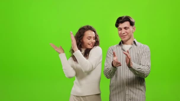 Un hombre y una mujer están de pie y aplauden. Están sonriendo. Están parados sobre un fondo verde. Pantalla verde. 4K — Vídeos de Stock