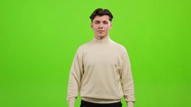 Adam ayakta duruyor ve kameraya bakıyor. Ellerini çırpıyor ve gülümsüyor. O, yeşil bir arka planın üzerinde duruyor. Yeşil ekran. 4K