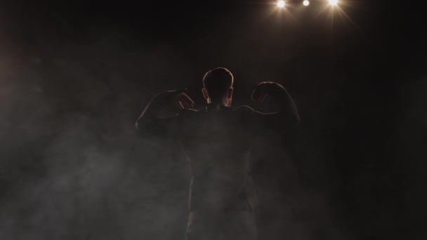 A man is standing on stage and waving his hands. The spotlight is shining on him. Theres smoke all around it. 4K — Stock Video