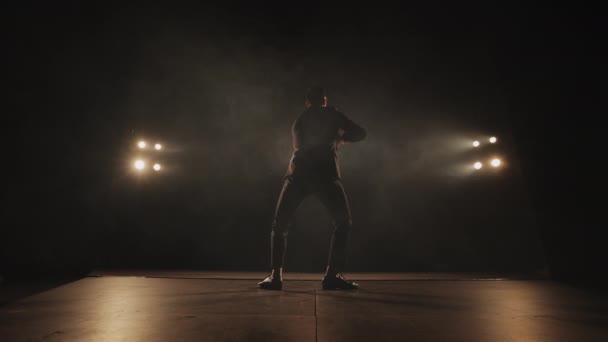 Un hombre está bailando tectónica y caminando sobre sus manos. El centro de atención está brillando sobre él. Lleva un traje. 4K — Vídeo de stock