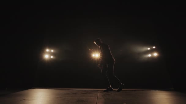 Ein Mann tanzt und rennt. Er steht im Rampenlicht. Er trägt einen Anzug. 4K — Stockvideo