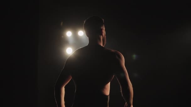一个穿紧身衣的男人正在舞台上表演.他在挥手。聚光灯照在他身上.4K — 图库视频影像