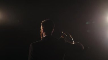 Adam kazananların kadehini kaldırıyor. Sahnede durup seyirciye bakıyor. Takım elbise giyiyor ve spot ışıkları onun üzerinde parlıyor. Kamera onun arkasında bir dönüş yapıyor. 4K