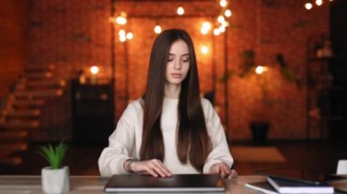 Bir kadın masada oturuyor ve bir dizüstü bilgisayar açıyor. O gülümsüyor. Ev ofisinde çalışıyorum. 4K