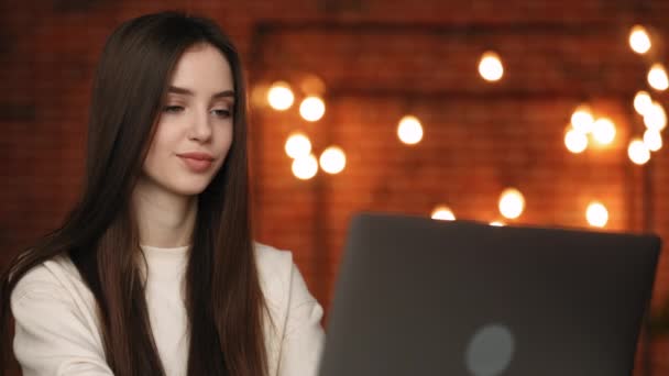 Uma mulher está sentada no seu escritório. Ela está sentada em sua mesa e trabalhando em seu laptop. Tiro de retrato. 4K — Vídeo de Stock