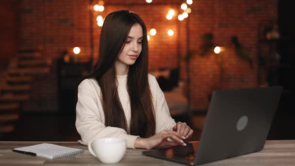 Bir kadın ev ofisinde oturuyor. Masasında oturuyor ve dizüstü bilgisayarı üzerinde çalışıyor. 4K — Stok video
