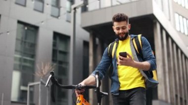 Yemek dağıtan adam gidiyor. Gülüyor ve konuşuyor. O bir bisiklet tutuyor ve omuzlarında büyük bir sırt çantası taşıyor. Kamera aşağıdan çekim yapıyor. Güzel İş Merkezi