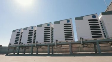 İş merkezinin çatısında altı klimadan oluşan bir klima sistemi bulunmaktadır. Kamerayı soldan sağa hareket ettiriyor. Güzel güneşli bir gün. 4K