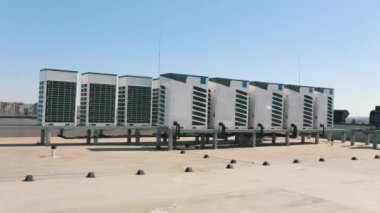 An air conditioning system of two rows of air conditioners is located on the roof of the business center. Moving the camera from left to right. Nice sunny day. 4K