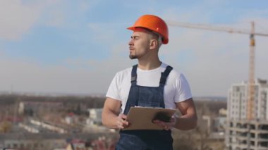 Genç mühendiste bir dosya dolusu belge ve akıllı telefon var. Dikkatlice başka tarafa bakıyor. Bir iş merkezinin çatısında. O, iş kıyafetleri ve sert bir şapka giyiyor. Yapım içeri