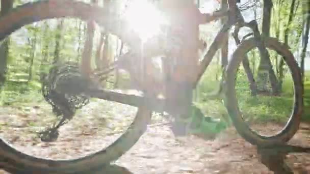 Un ciclista sta pedalando in MTB lungo un sentiero forestale. Sta saltando sulla collina. Primo piano di un ciclista che pedala. Il sole splende nella telecamera. 4K — Video Stock