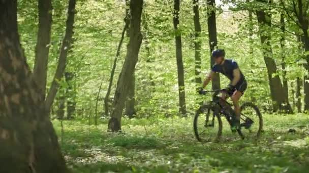 Rowerzysta jeździ rowerem MTB po leśnej ścieżce. Ma na sobie sprzęt rowerowy. Kamera go śledzi. 4K 50fps — Wideo stockowe