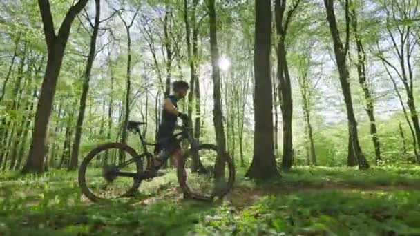 Il ciclista sta camminando accanto alla bici. Indossa l'attrezzatura da ciclismo. La telecamera si muove con lui. 4K — Video Stock