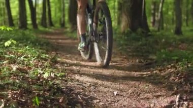 Bir bisikletçi orman yolunda yüksek hızda gidiyor. Bisiklet kıyafeti giyiyor. Arkadan ateş ediyorlar. MTB bisikleti üzerinde antrenman. 4K 