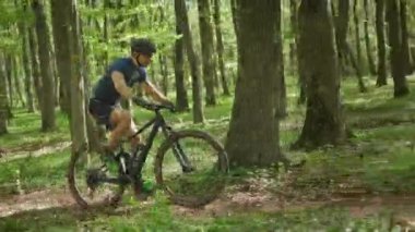 Bir bisikletçi bir orman yolunda ilerliyor. MTB bisikleti üzerinde çalışıyor. Bisiklet üniforması giyiyor. 4K 
