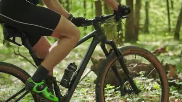 Un ciclist merge pe o cale forestieră. Camera se concentrează pe faptul că pedalează. Instruire pe o bicicletă MTB. El merge de la stânga la dreapta. 4K — Videoclip de stoc