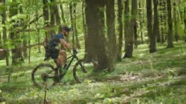 Bir bisikletçi ormanda yokuş yukarı gidiyor. MTB bisikleti üzerinde çalışıyor. Bisiklet üniforması giyiyor. 4K 