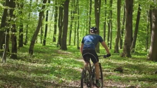 Un ciclista sta cavalcando lungo un sentiero forestale. Le foglie stanno volando via da sotto le ruote. La telecamera si muove da sinistra a destra e spara da dietro. 4K — Video Stock