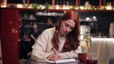 Kafeteryada oturan kızıl saçlı, beyaz bir kadın. Belgeler hakkında notlar alıyor. Kadın yakınlardaki bir masada içki içerek evrak işleriyle uğraşıyor. Odaklanmış öğrenci ya da serbest çalışan rahat bir kahve dükkanında okuyor..