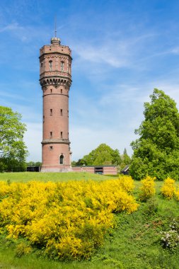 Dutch stone water tower with blooming yellow flowers clipart