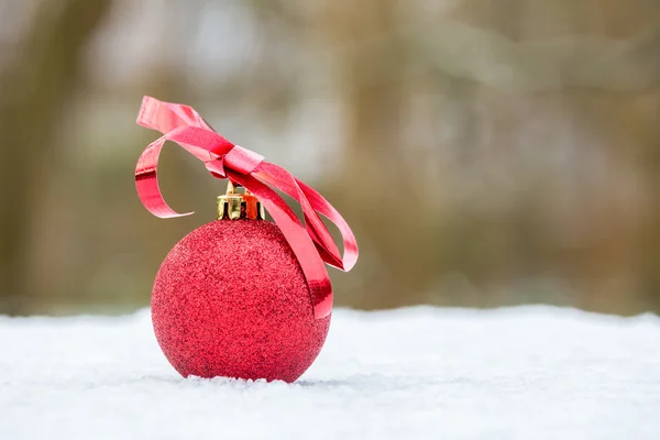 Rote Christbaumkugel mit Schleife draußen im Schnee — Stockfoto