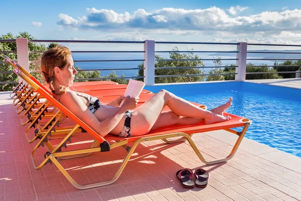 Caucasian woman sunbathing and reading book — Stock Photo, Image