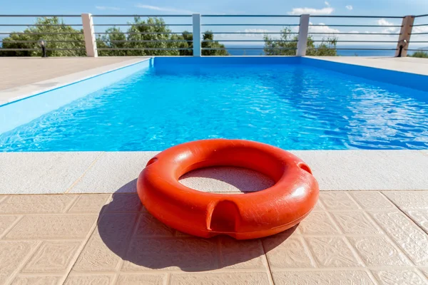 Boa di salvataggio arancione alla piscina blu — Foto Stock