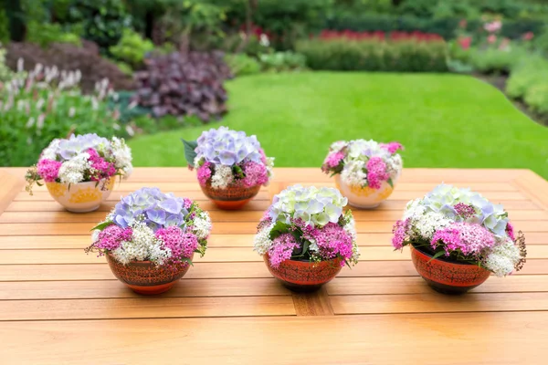 Vases with blooming flowers on teak table — Stock Photo, Image